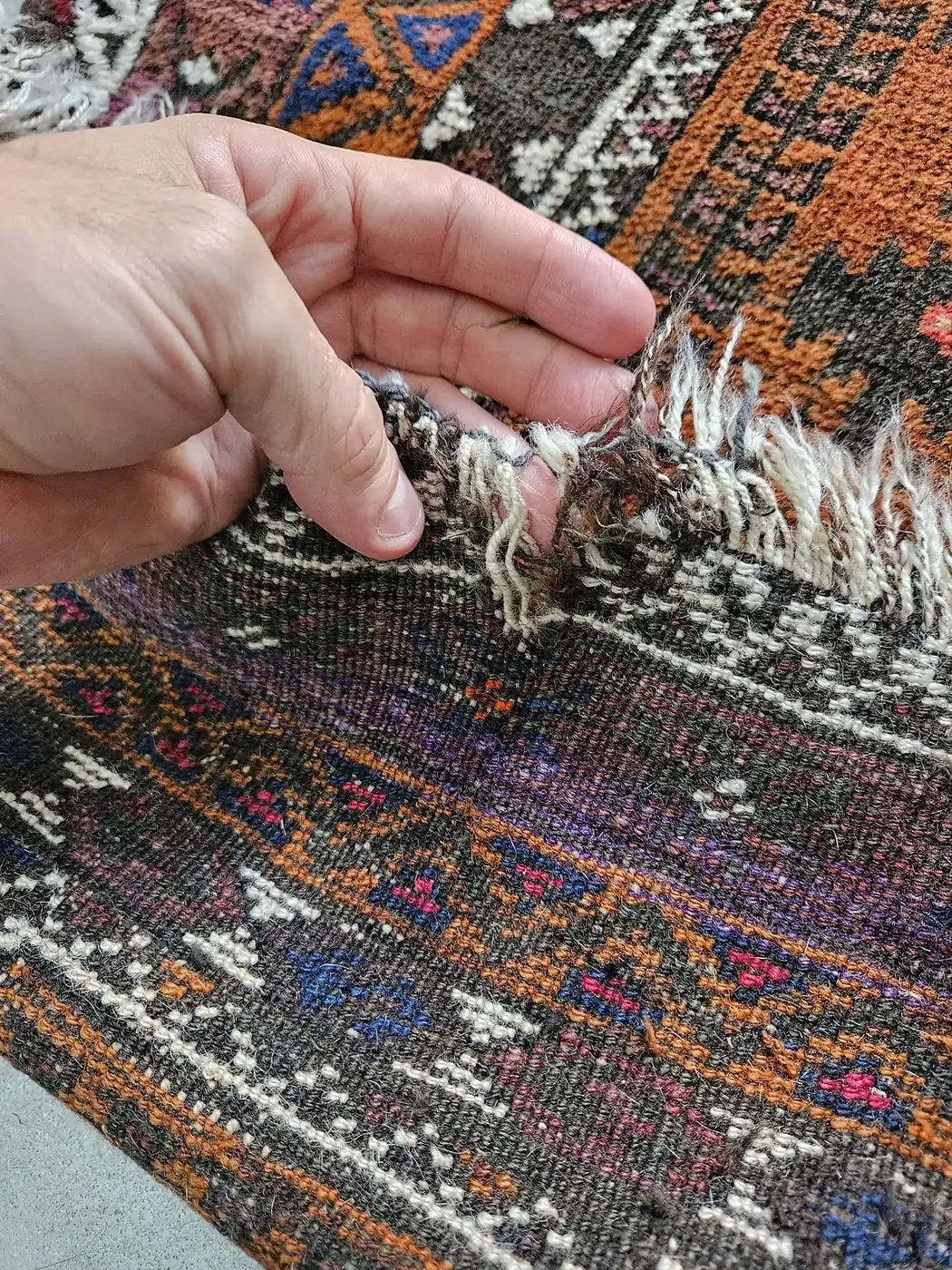Hands working the fringe of a tribal rug