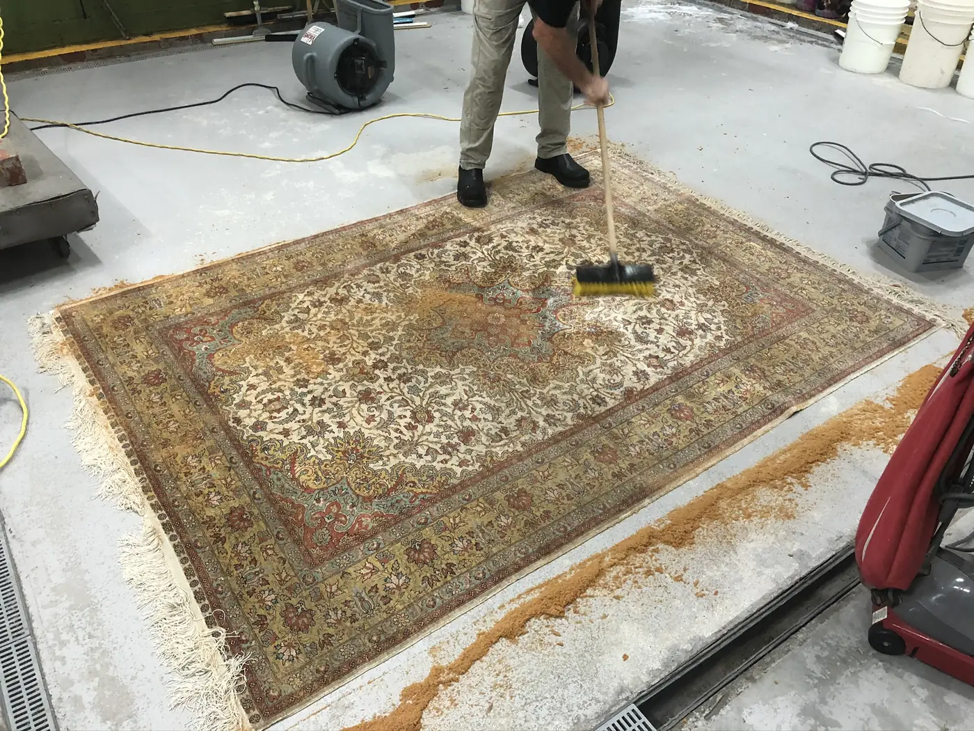 A Persian rug being brushed with suds on the wash floor